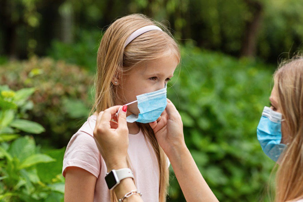 Adult helping child put on a face mask