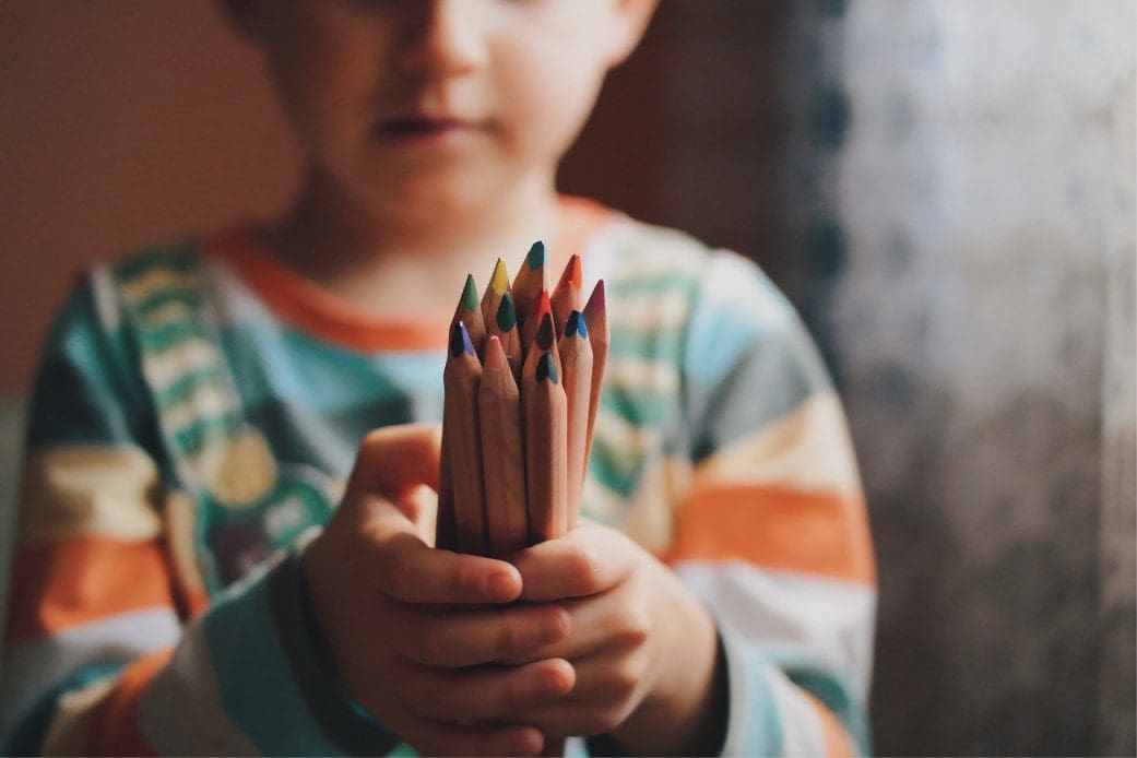 Child holding colored pencils