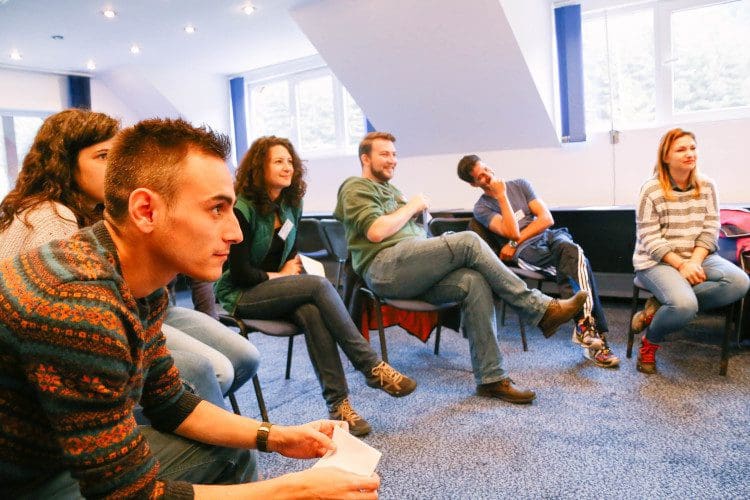 Group of people sitting in a circle talking in group therapy.