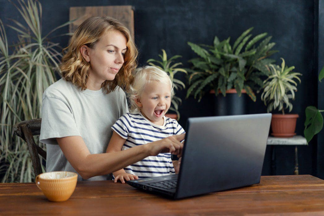 Mother and child on computer in virtual speech therapy.