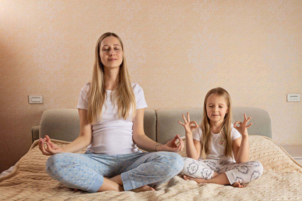 Mother and daughter meditating together.