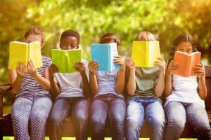 Five children reading books in the park