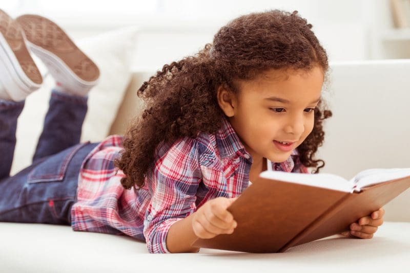 Young child reading a book in bed